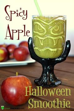 a halloween smoothie in a glass on a table with an apple next to it