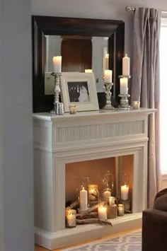 a living room with a fire place and candles on the mantel in front of it