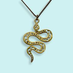 Decorated serpent pendant on antiqued brass chain. Metal: 24kt gold plate over brass on pendant, aged brass chain Size: 1.5" L pendant Available on 16", 18", or 20" chain Lobster Clasp Brass Pendant Box Chain Necklace, Brass Snake-shaped Necklace For Gifts, Symbolic Hand Forged Brass Necklaces, Bronze Brass Chain Necklace For Gift, Symbolic Hand Forged Brass Necklace, Vintage Brass Box Chain Necklace, Gold Oxidized Finish Chain Necklace As Gift, Gold Chain Necklace With Oxidized Finish As Gift, Antique Brass Chain Necklace As Gift