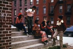 young people sitting on steps in front of brick buildings