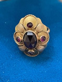 Victorian petaled fairy ring 14k yg 565 in bohemian garnet 4.7 total gms circa 1900's. This is such a beautiful ring size 6 US. It has a large faceted stone in the middle and 4 tiny stones in the side. A great gift for Mother's Day or Christmas. Ornate Gold Ruby Ring, Antique 14k Gold Amethyst Ring, Ornate Gold Ring With Ruby, Vintage Multi-stone Ruby Ring In 14k Gold, Ornate Gold Rings With Ruby, Gold Garnet Ring With Rose Cut Diamonds, Gold Rings With Rose Cut Diamonds And Garnet, Antique 14k Yellow Gold Ruby Ring, Antique Ruby Multi-stone Jewelry