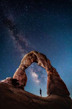 a man standing in front of an arch under the stars