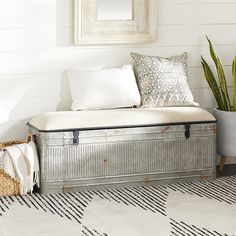 a metal box sitting on top of a white floor next to a potted plant