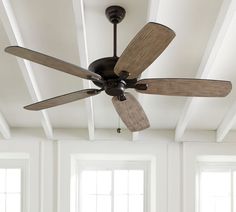 a ceiling fan in a room with white walls and wood trimmings on the ceiling