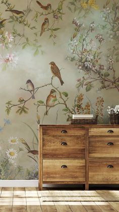 a wall with birds on it and flowers painted on the wall behind it is a dresser