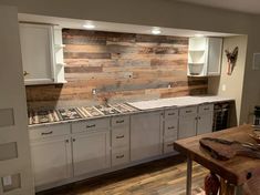 a large kitchen with white cabinets and wood wall covering the backsplash, along with an island countertop