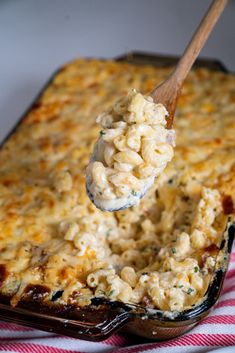 a spoon full of macaroni and cheese being lifted from a casserole dish