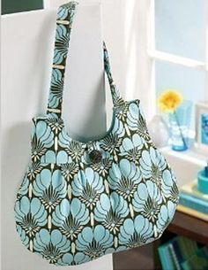 a purse hanging from the side of a white wall next to a blue flowered bag