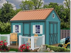 a small blue shed sitting on top of a lush green field next to a wooden fence