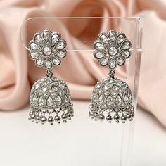 "These silver-plated polki jhumka earrings are a stunning addition to any outfit. The intricate detailing and beautiful silver beaded accents add an elegant touch to this Bollywood inspired piece, while polki stones give it a gorgeous sparkle that's sure to catch light and make heads turn. Length 1.7\" | Width 1\" Items are carefully packed and ready for gifting. All pictures are taken in natural light please allow for slight variations in color due to camera settings. Jewelry Care ✨Protect your Festive Silver Crystal Earrings, Bollywood Silver Dangle Chandelier Earrings, Silver Bollywood Chandelier Dangle Earrings, Silver Bollywood Jhumkas With Matching Earrings, Silver Bridal Earrings With Intricate Design For Diwali, Silver Bollywood Chandbalis For Pierced Ears, Silver Bollywood Style Drop Jhumkas, Silver Bollywood Dangle Earrings, Bollywood Style Silver Chandelier Earrings For Festivals