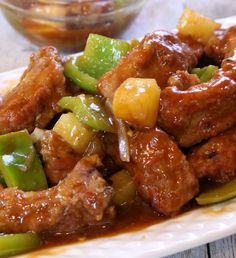 chicken and pineapple stir fry on a plate next to a small bowl of sauce