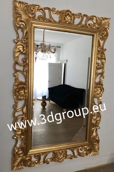 an ornate gold framed mirror hanging on the wall in a room with a chandelier