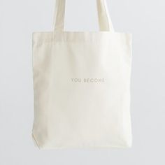 a white tote bag with the words you become printed on it