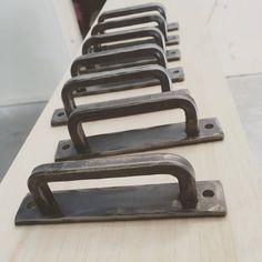 a row of metal handles sitting on top of a wooden table next to each other