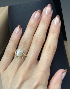 a woman's hand with a ring on it and her nails in the foreground