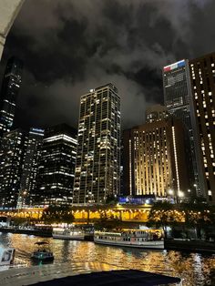 the city is lit up at night with boats in the water