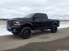 a black truck is parked on the side of the road in front of some snow