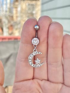 someone is holding their belly ring with the moon and star dangling from it