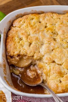 an apple cobbler recipe in a white casserole dish with a serving spoon