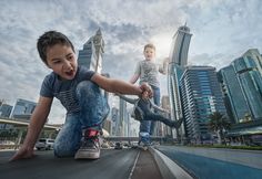 two young boys are playing on the street in front of tall buildings and skyscrapers