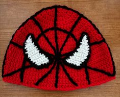 a crocheted spiderman hat with wings on it sitting on a wooden surface