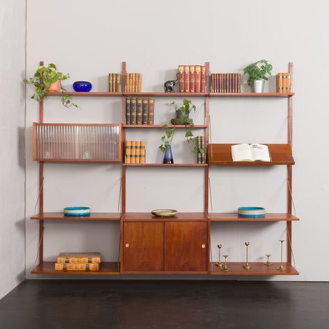 Danish mid century modern teak 3-bay wall unit made in the 1960s made by PS system, Randers, designed by Preben Sorensen. It is a fully modular shelving system with interchangeable parts that can be arranged upon one's need. Two cabinets and nine shelves provide just enough space for storage and exposing a lot of books and decorations. The whole set is veneerd in beautiful  rich grain teak and  hangs on solid wood rails using brass hangers. Especially noteworthy are the brass details of the cabi Mid Century Shelving, Mid Century Modern Shelves, Desk Wall Unit, Teak Wall Unit, Modular Shelving System, Oak Bookcase, Vintage Shelf, Teak Wall, Danish Mid Century Modern