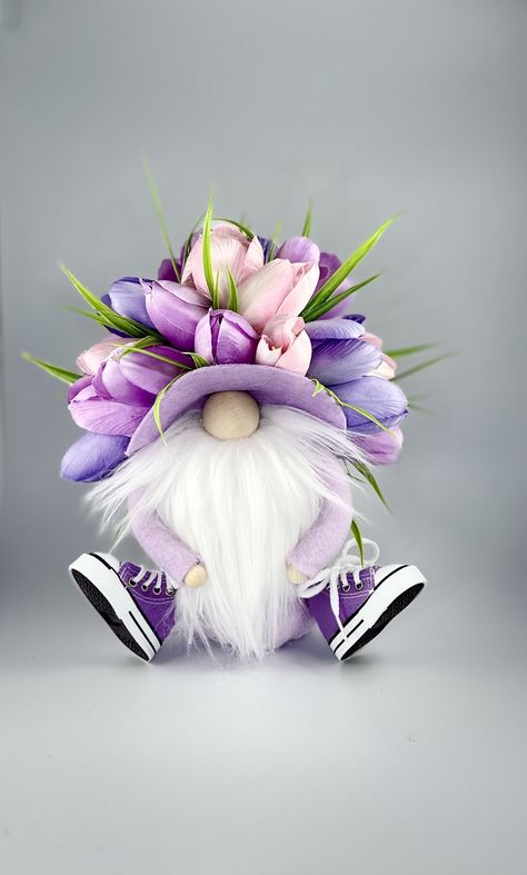 This special gnome is ready for shine! Dressed in high-top sneakers this playful gnome is designed to bring joy and charm to any setting. His beautiful floral bonnet, adorned with an abundance of tulips, showcases vibrant colors that add a cheerful touch to your decor. Standing out with his whimsical and detailed design, this gnome is not just a decoration but a piece of art. The high-top sneakers add a modern twist, while the lavender body exudes a calming and soothing presence. The floral bonn Dollar Tree Gnome Diy, Gnome Projects, Gnome Dog, Stuffed Gnomes, Tree Gnome, Spring Gnomes, Gnome Diy, Scandinavian Folklore, Handmade Gnomes