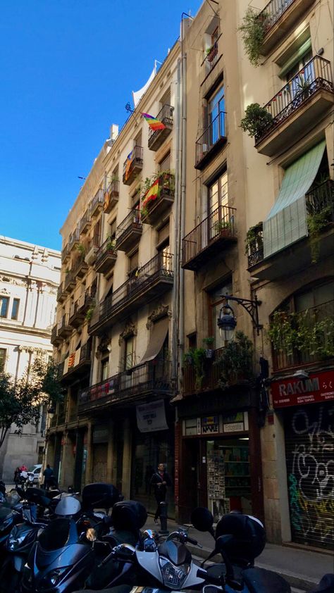 yellow barcelona apartment building with balconies. on all the balconies there are plants and some balconies have the spanish flag or the pride flag. shows the barcelona aesthetic. Barcelona Apartment Exterior, Barcelona Apartment Balconies, Apartment In Barcelona, Barcelona Apartment Aesthetic, Spain Apartment Aesthetic, Study Abroad Madrid, Barcelona Buildings, Apartment In Spain, Spain Apartment