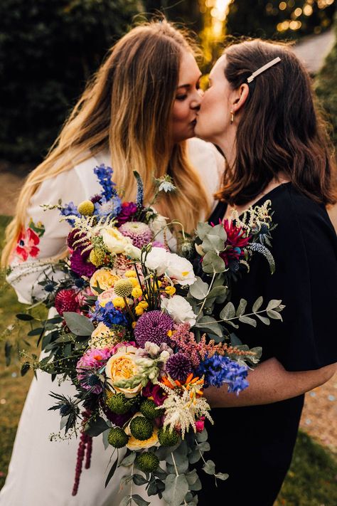 Colourful wildflower wedding bouquet with pink, purple, and yellow flowers held by two brides Cute Couple Wedding, Lesbian Wedding Outfits, Rainbow Wedding Theme, Couple Wedding Photography, Purple And Yellow Flowers, Wildflower Wedding Bouquet, Colorful Wedding Bouquet, Wedding Readings, Embroidered Wedding Dress