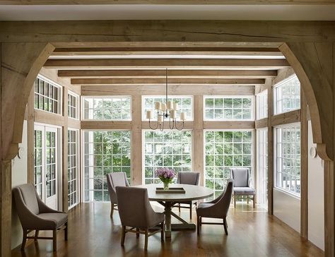 Elegant dining room features a Vendome Large Chandelier hung from a stunning rustic wood ceiling beams above a round salvaged wood dining table seating four gray upholstered dining chairs. Circa Lighting Sunroom Dining Room, Wood Ceiling Beams, Sunroom Dining, Fall Dining Room, Cottage Dining Rooms, Transitional Dining Room, Transitional Dining, Autumn Dining, Scout Guide