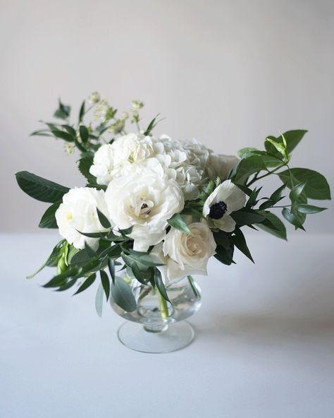 Classic, organic green and white reception centrepiece arrangement with greenery, white ranunculus, white anemone, white hydrangea and white roses in a clear glass pedestal vase White Flower Arrangements, Table Flower Arrangements, White Ranunculus, Flowers And Greenery, White Anemone, Reception Centerpieces, Wedding Table Flowers, Wedding Arrangements, White Hydrangea