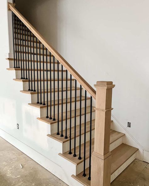 A neutral room features white stairs and oak wood treads. The oak is coordinated with a matching wood banister. Black railings contrast with the muted palette of the space. Wood Staircase Ideas, White And Wood Staircase, Wood Banister, Black And White Stairs, Redo Stairs, Metal Stair Railing, White Staircase, Black Stairs, Stair Banister