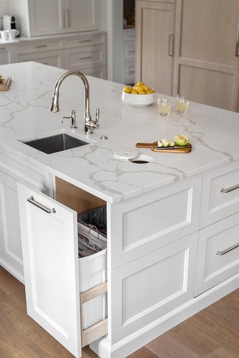 A gorgeous white kitchen island boasts a pull-out trash can fitted beneath a round cut out in a statuary quartz countertop. Transitional Bathroom Design, Gorgeous White Kitchen, Kitchen Island Tops, Grey Kitchen Island, Oak Trim, White Shaker Cabinets, White Kitchen Island, Island Countertops, Studio Kitchen