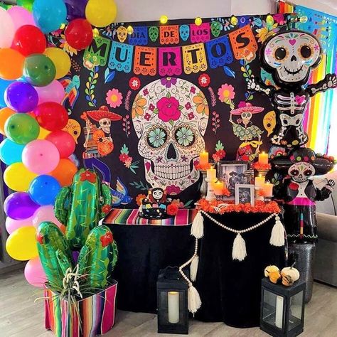 Enliven your “Day of the Dead” altar by decorating a vinyl backdrop with assorted colored balloons & bulb string lights. Adorn the table with a black tablecloth & layer a Mexican serape runner on top to exude flamboyance. Also, scatter orange marigold flowers and hang a wood bead tassel garland at the front of the table. Use pillar candle holders to display the candles on the table and set LED candles in black candle lanterns placed on the floor adding a dramatic appeal to your setup. Day Of The Dead Altar, Wood Bead Tassel, Event Decor Ideas, Party Decorations Table, Orange Marigold, Black Tablecloth, Flowers Candles, Marigold Flowers, Light Party