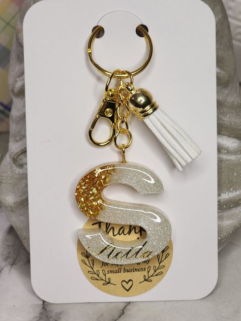 "Beautiful Handmade Gold and Pearl with Gold Stones Keychain. This keychain is personalized with the name of your choice in a cursive font. Please choose the Letter you would like from the drop down box above :)  ITEM DETAILS: ・This is a listing for 1 Resin Keychain ・The chain is gold colored stainless Steel ・The Keychain Letter Charm charm is approximately 1.50 in. x 1.50 in. in size ・I will package your Keychain in a cute reusable organza gift bag - perfect for gift giving. IMPORTANT: ・Please note, in order to keep your jewelry in the best condition, it is suggested to keep jewelry out of contact with any water, chemicals and/or strong perfumes. ・All Letters may slightly differ in color as each one is uniquely made to order. Any other amendments you would like to be made, please feel fre J Resin Keychain, S Letter Resin Keychain, Pearl Resin Keychain, Acrylic Letter Keychain, Glitter Resin Keychain, Epoxy Resin Keychain Diy, Resin Keychain Packaging Ideas, Resin Packaging Ideas, New Business Gift Ideas