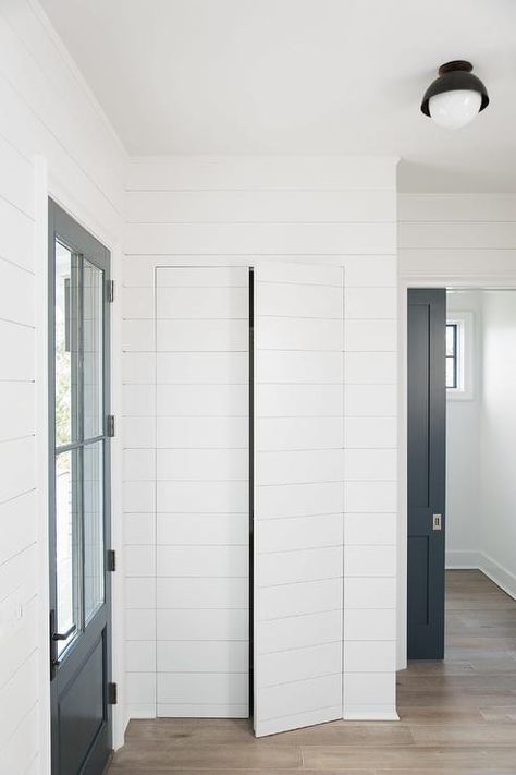 A foyer closet is concealed behind white shiplap jib doors positioned adjacent toa. black door with 4 glass panels. Cortney Bishop Design Jib Door, Secret Door Ideas, Cortney Bishop, Hidden Doors In Walls, Foyer Closet, Diy Doors, Staining Wood Floors, Gray Stained Wood, Hidden Closet