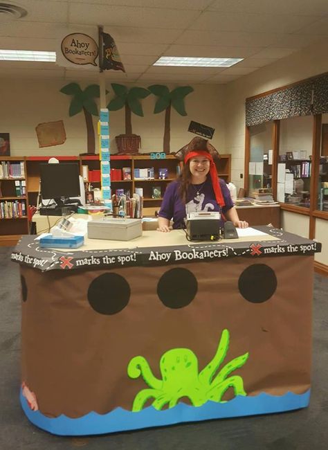 My amazing assistant turned our circulation desk into a pirate ship for our "bookaneer"-themed Book Fair! Pirate Book Fair, Book Fair Themes, Pirate Office, Gray Library, Book Fair Ideas Display, Library Windows, Purple Pirate, Pirate Theme Classroom, Circulation Desk