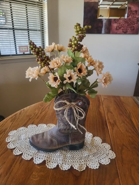 This is my 2nd decorated cowboy boot with flowers. Makes a nice rustic western look. The twine bow sets it off nicely. I stuffed the boot with heavy brown paper to keep it looking full and not tipping over. The doily gives it a nice country look. I love to upcycle/repurpose items. Cowboy Boots Decor Ideas, Boot Vase Centerpiece, Cowgirl Boot Flower Arrangement, Crafts With Cowboy Boots, Cowboy Boot Repurpose Ideas, Country Flower Arrangements Rustic Decor, Decorating With Cowboy Boots, Cowboy Flower Arrangement, Cowboy Boot Planter Ideas