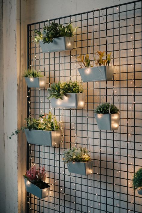 Cascading greenery and potted plants attached to a black metal grid on a living room wall. Wall Mounted Plant Shelves, Plant Shelves On Wall, Apartment Plant Wall, Slat Plant Wall, Wall Plants Indoor Living Rooms, Indoor Wall Planter Ideas, Hanging Plants Indoor Ideas, Live Plant Wall, Plant Wall Ideas Indoor