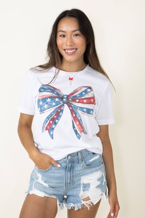 Showcase your patriotism all season long with this Americana Bow Graphic T-Shirt for Women in White! Stylish and comfy, it features short sleeves, ribbed crew neckline, and a screen-printed Americana Bow graphic in a fun red, white and blue pattern. Perfect for making a statement or just loungin' around! Features: A. Blush Style: 11931X-TS-WHITE Color: White 100% Cotton Women’s graphic tee Short sleeves, ribbed crew neckline Screen printed graphic of an American bow in a red, white and blue pattern Measurements from size small: Length from front shoulder: 28” Chest: 34" Machine wash warm inside out, tumble dry low Paint Therapy, White And Blue Pattern, American Flag Clothes, Bow Graphic, Women In White, Fourth Of July Shirts, Bow Shirts, T Shirt For Women, White Style