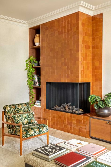 A tile-covered fireplace surround makes a bold statement in this living room. Fireplace Midcentury Modern, Brick Fireplace In Living Room, 1970 Fireplace, Mcm Fireplace Wall, Fireplace Next To Stairs, Mid Century Electric Fireplace, Cover Up Brick Fireplace, Midcentury Fireplace Ideas, Terracotta Tile Fireplace