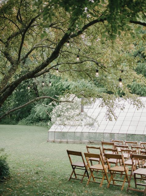 Greenhouse wedding ceremony; Wooden folding chairs; String lights Wooden Folding Chairs Wedding, Greenhouse Wedding Ceremony, Mix Match Chairs, Farm Wedding Ceremony, Glass House Wedding, The Glass House, Wooden Folding Chairs, 2025 Wedding, Greenhouse Wedding