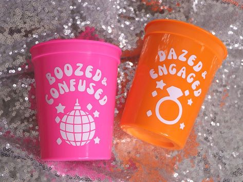 Let's go BACH to the 70s for a retro themed bachelorette! Have your whole tie dye, disco ball & covered-in-silver-glitter bachelorette gang drinking in style with these themed plastic stadium cups.  🆃🅾  〰️Choose from designs -  DAZED & ENGAGED or BOOZED & CONFUSED. 〰️Choose the amount and color of the cups you would like to order.  〰️Don't forget to purchase a white cup for the bride! 〰️Scroll through the product listing's photos for cup colors and shipping options.   〰️Each stadium cup holds Bachelorette Party Ideas 70s, Bachelorette Party Themes 70s, 70s Disco Bachelorette Party, Retro 70s Bachelorette Party, Dazed And Engaged Bachelorette Decor, Groovy Bachelorette Party Theme, Retro Cowgirl Bachelorette Party, Boozed And Confused Bachelorette, Bachelorette Party Retro Theme