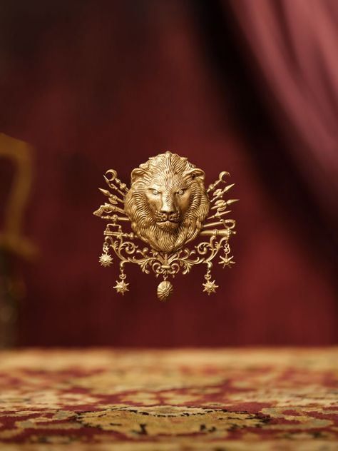 A brilliant piece of jewellery, the Ottoman Brooch is a must-have adornment. This brooch is designed by keeping the lion's face in the centre and carving various weapons and star dangles towards the outer edges. The eyes of the beast as looking as wild as they could which adds to the overall beauty of the brooch Gold Ottoman, Lion Brooch, International Men's Day, Brooch Design, Men's Brooch, The Ottoman Empire, Brooch Men, Lucky Stone, Vintage Bangles