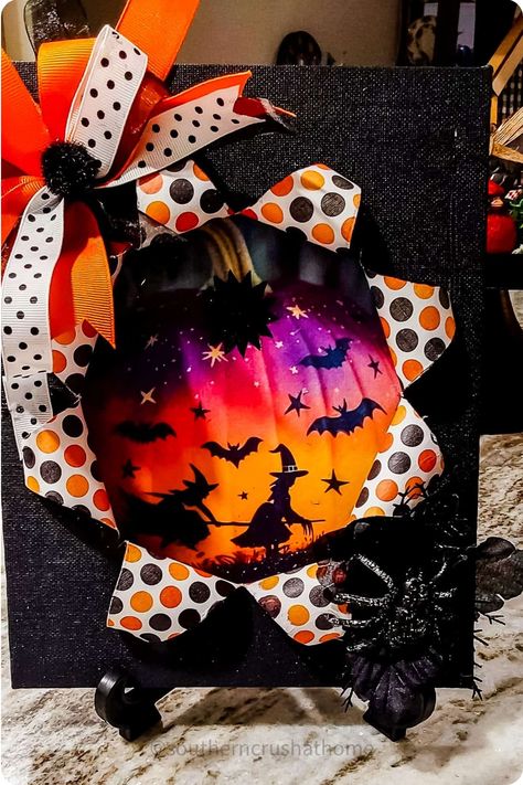 Halloween-themed decoration featuring a starburst design with bats, witches, and a spider, accented with polka dot and orange ribbons. Breakout Canvas Craft, Halloween Busted Canvas Diy, Halloween Busted Canvas Ideas, Break Out Canvas, Exploding Canvas, Bursting Canvas, Crafts With Canvas, Pop Out Pictures, Busted Canvas Crafts Halloween