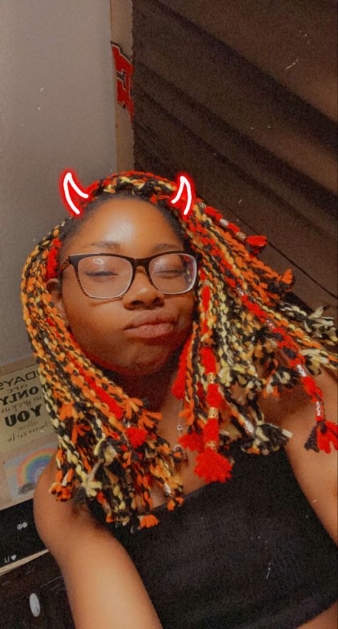 Black Girl with nerdy glasses and Yarn Twists in the colors: red, orange, yellow, and black. Some twists have hair cuffs in the colors gold and silver. Facial expression is silly with a Snapchat filter that puts neon red devil horns on the head. Yarn In Hair, Twists Short Hair, Fire Braids, Twists Short, Yarn Twists, Hairstyles Protective, Yarn Twist, Yarn Braids, Wool Dreads