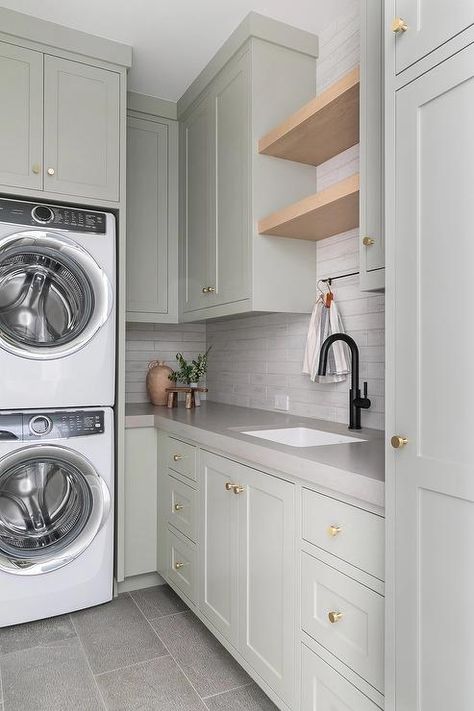 A stacked white front loading washer and dryer are enclosed beneath light gray green cabinets. Transitional Laundry Room, Grey Laundry Rooms, White Laundry Rooms, Laundry Room/mud Room, Green Laundry, Dream Laundry Room, White Laundry, Laundry Cabinets, Mudroom Laundry Room