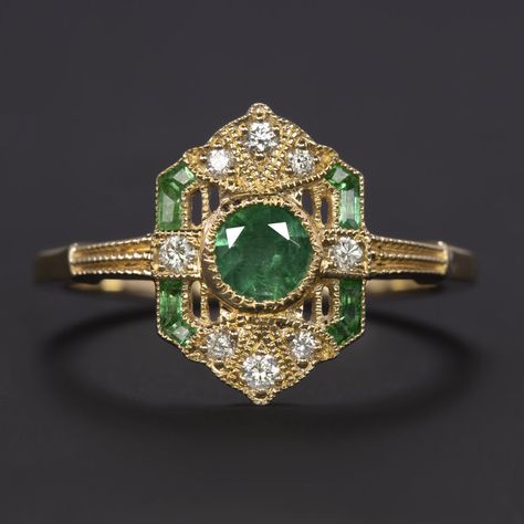 Why we love it:This diamond and emerald ring is beautifully crafted with a geometric Art Deco style design and encrusted with glittering diamonds and spring green emeralds!Highlights:- 0.43ct natural emerald center with gorgeous, well saturated color- Calibre cut natural emerald accents with bright green color- 0.10ct of high quality diamond accents- Unique and elegant vintage style design- 14k yellow gold settingDimensions:13.0mm across (north-south) and 2.9mm from the finger to the top of the ring