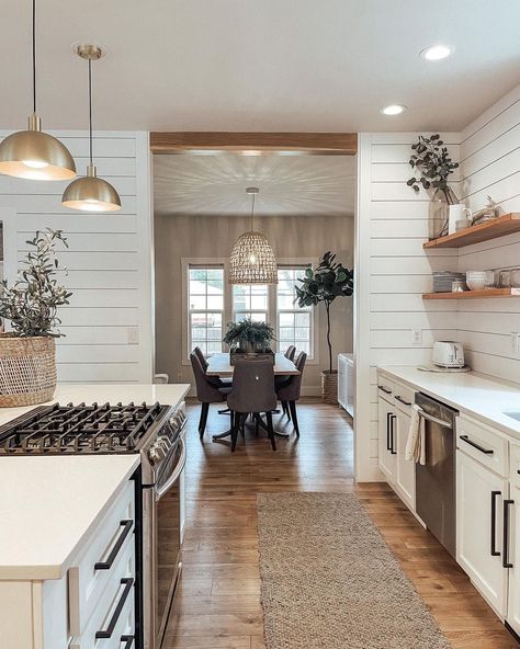 Gaze through a shiplap doorway into a dining room decorated by the light shining through a rattan pendant. A love for stylish lighting is apparent, with two golden pendants suspended above a white kitchen countertop. Create a smooth transition between adjoining spaces with little tricks like using the same lighting style, even if they aren't the same design. Kitchen Pass Through Ideas, Kitchen Pass Through, Kitchen Pass, Kitchen Pendant, American Houses, Rattan Pendant, Kitchen Ceiling Lights, Stylish Lighting, Kitchen Pendants