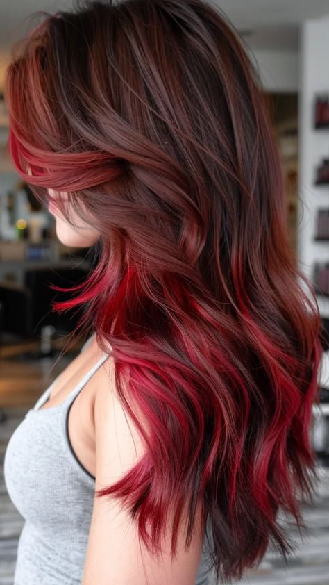 Woman with long, wavy hair dyed in dark brown and vibrant red highlights. Brown Hair With Dark Red Highlights, Medium Brown Hair With Red Highlights, Deep Red Balayage, Brunette Hair With Red Highlights, Dark Red Hair With Highlights, Cherry Red Highlights, Red Highlights On Black Hair, Red Highlights On Dark Hair, Red Hair Highlights